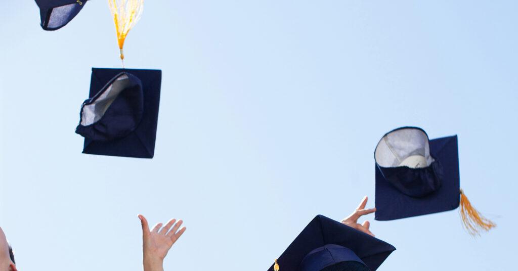 Graduate students throwing hats in the air.